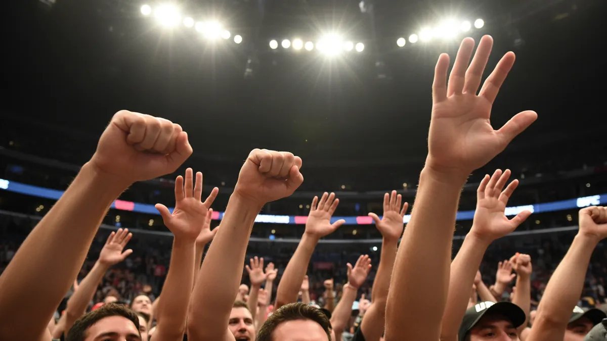 Manos de aficionados levantadas en las gradas de la UFC tras un combate.